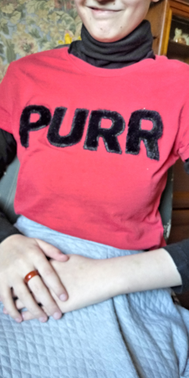 Me wearing a red T-shirt with a tactile writing of the word "Purr" on it.